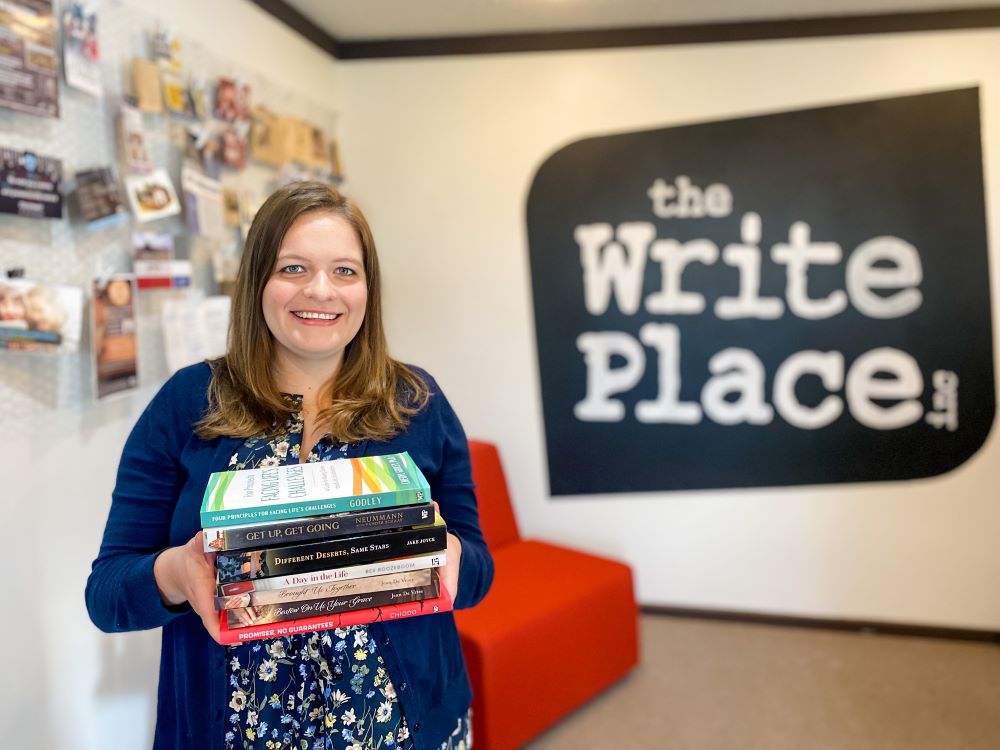 Sarah Purdy holding stack of books in Write Place office