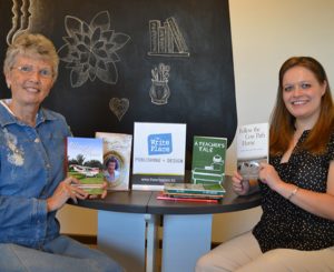 Carol Van Klompenburg and Sarah Purdy display memoirs that have been published by the Write Place.