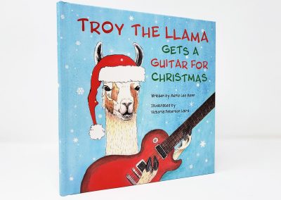 Troy the Llama Gets a Guitar for Christmas book photo, showing illustration of Troy the llama holding a red guitar, wearing a santa hat