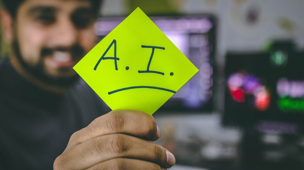 Man holding bright green sticky note with the word "A.I." written on it