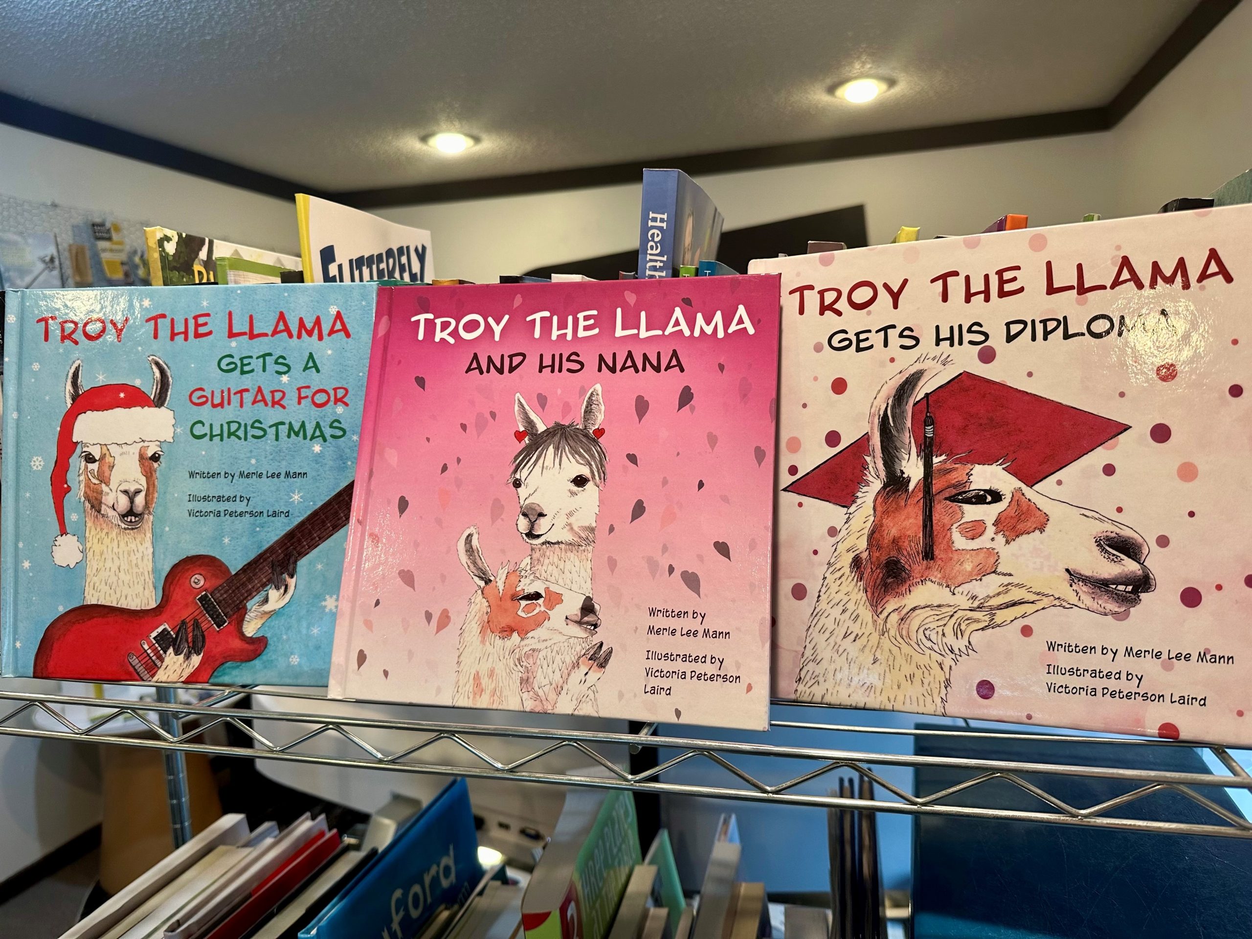 All three Troy the Llama books on a bookshelf