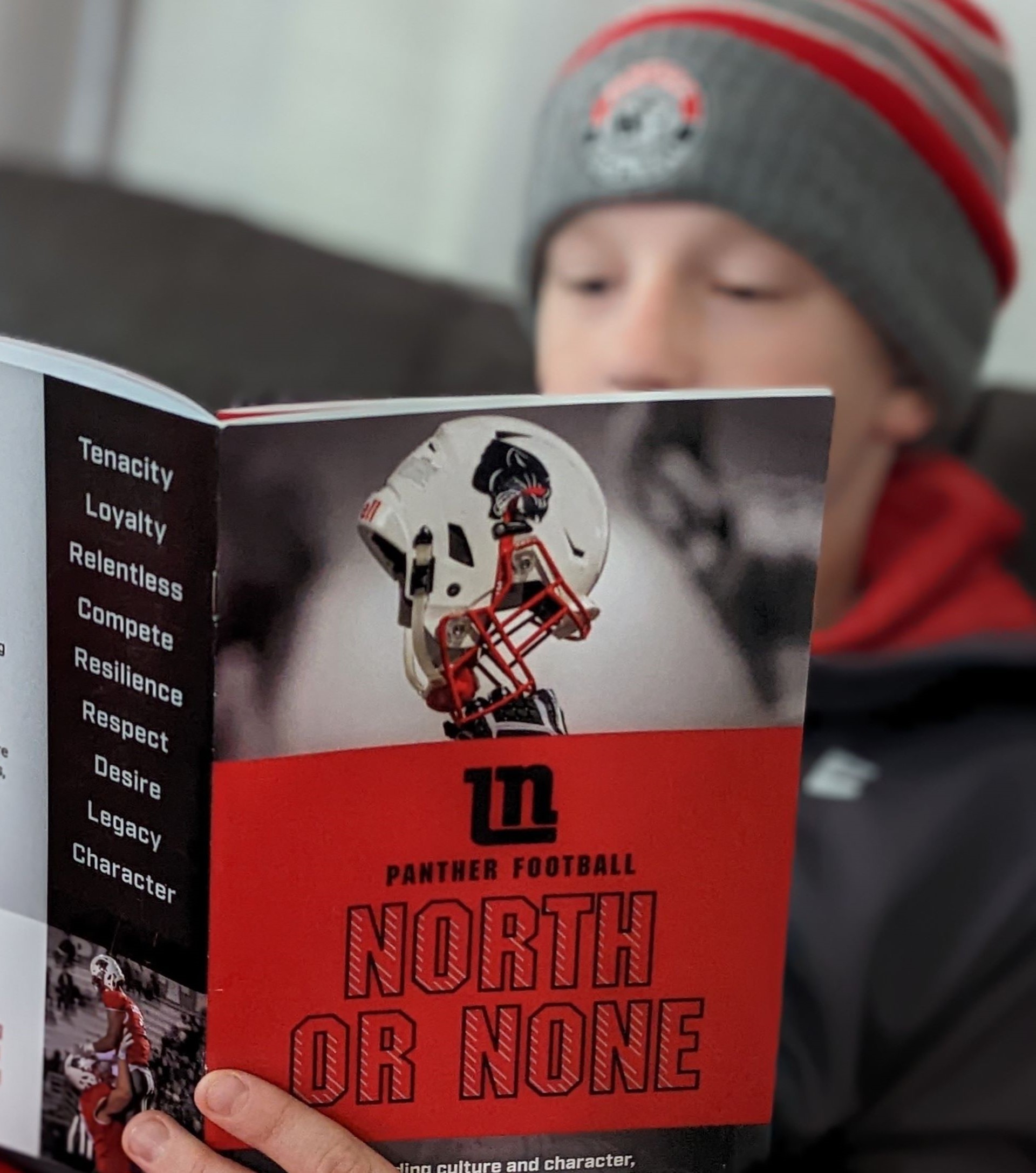 Closeup of boy in stocking cap reading North or None handbook