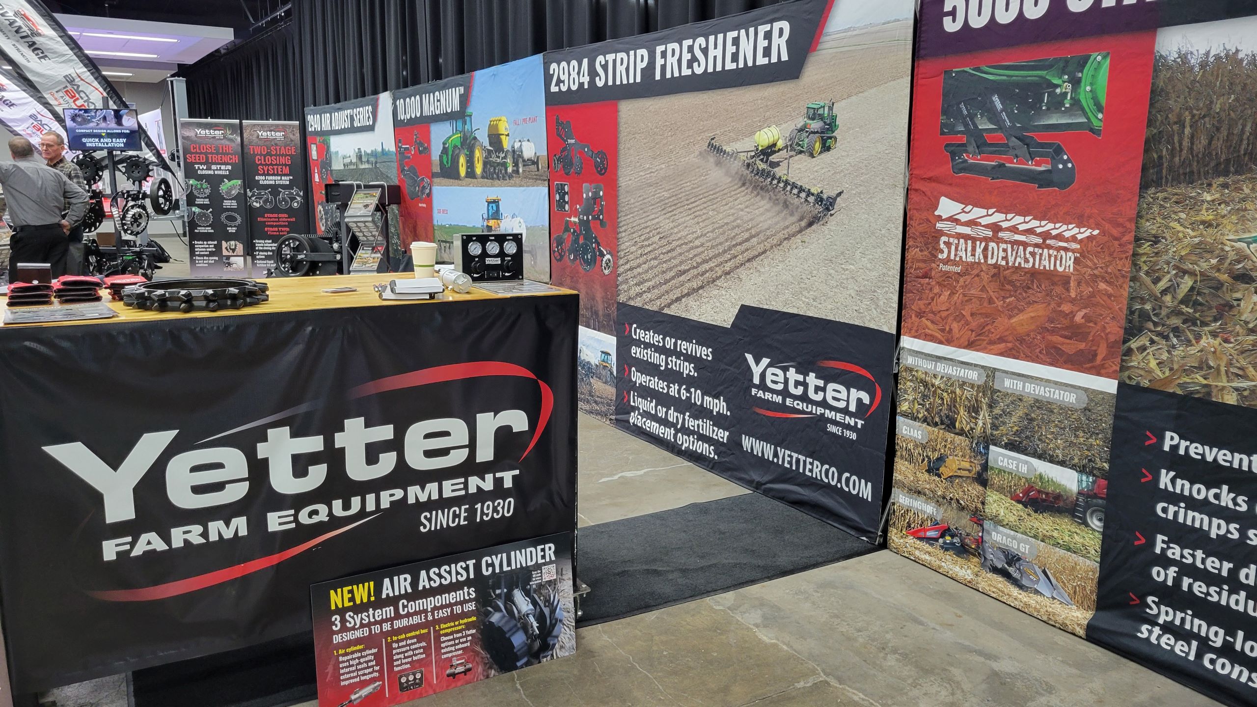 Yetter booth at trade show with signage, posters, and table with products